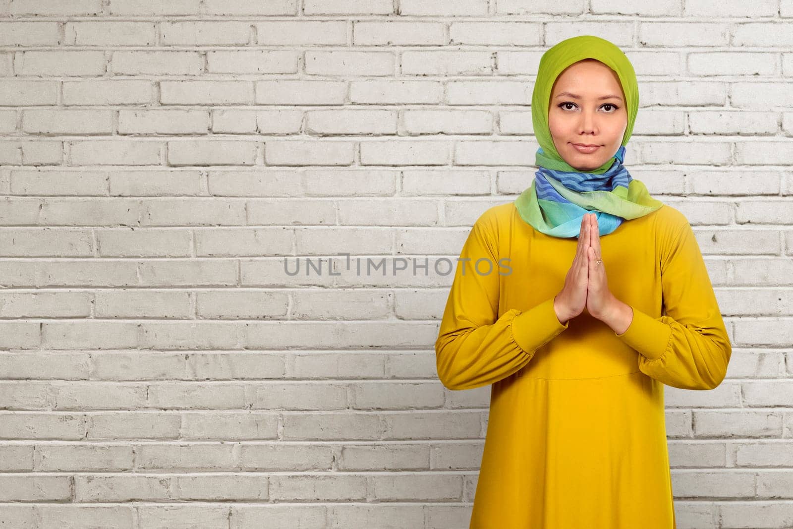 Asian muslim woman praying over white wall background