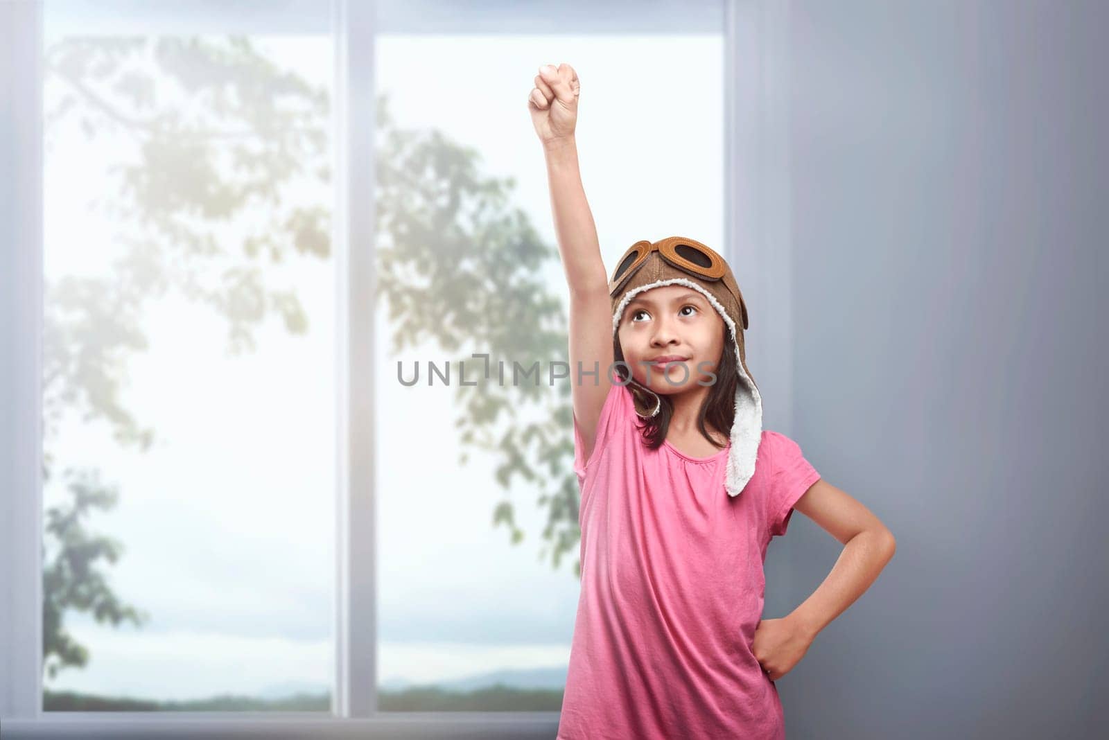 Beautiful asian kid in aviator helmet dreaming of being a pilot at home