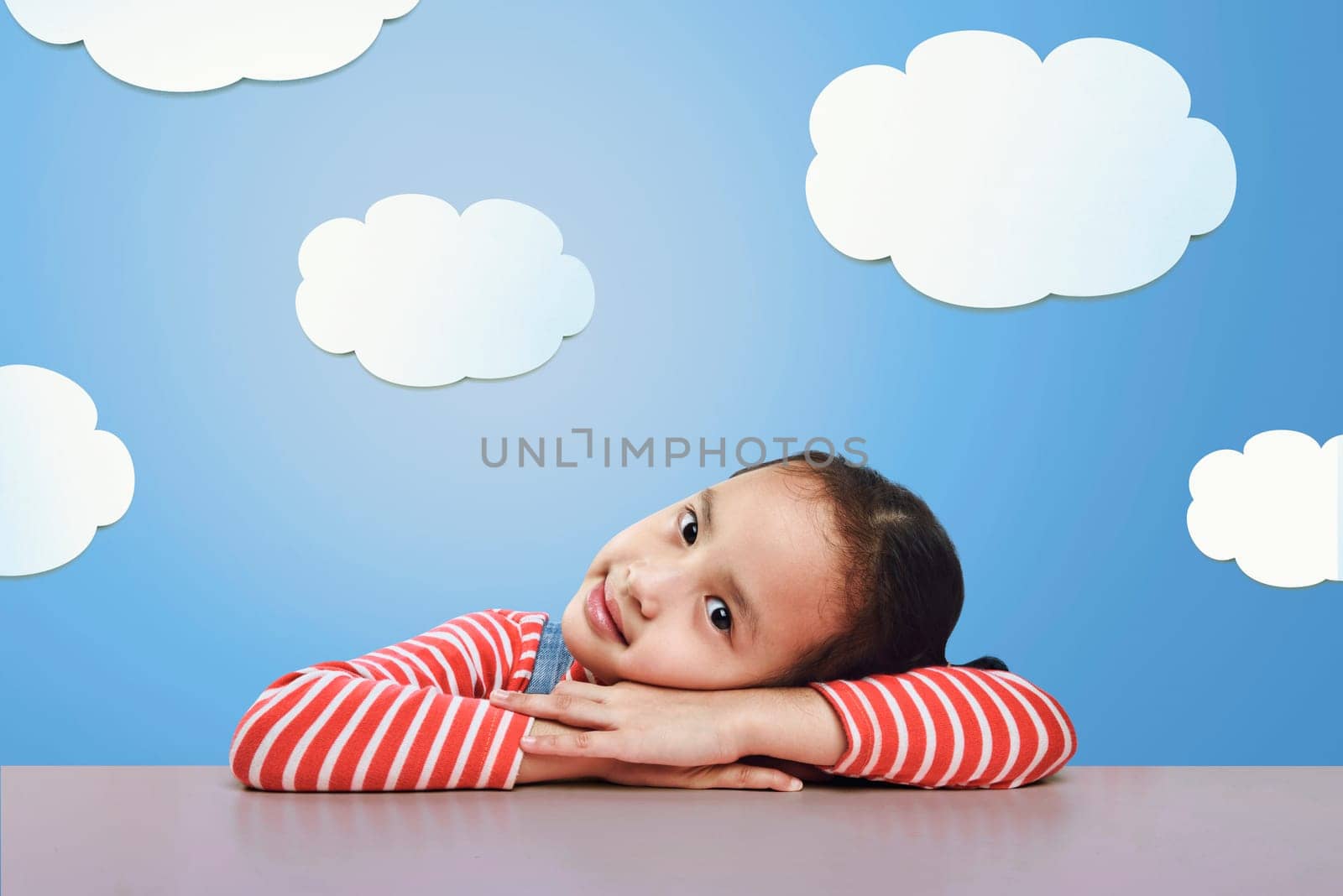 Beautiful asian little girl lying down on the desk with funny background