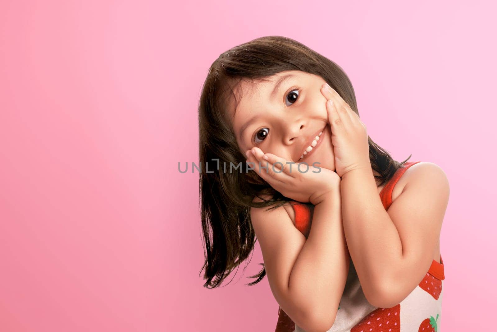Young asian kid smiling with happy expression over pink background