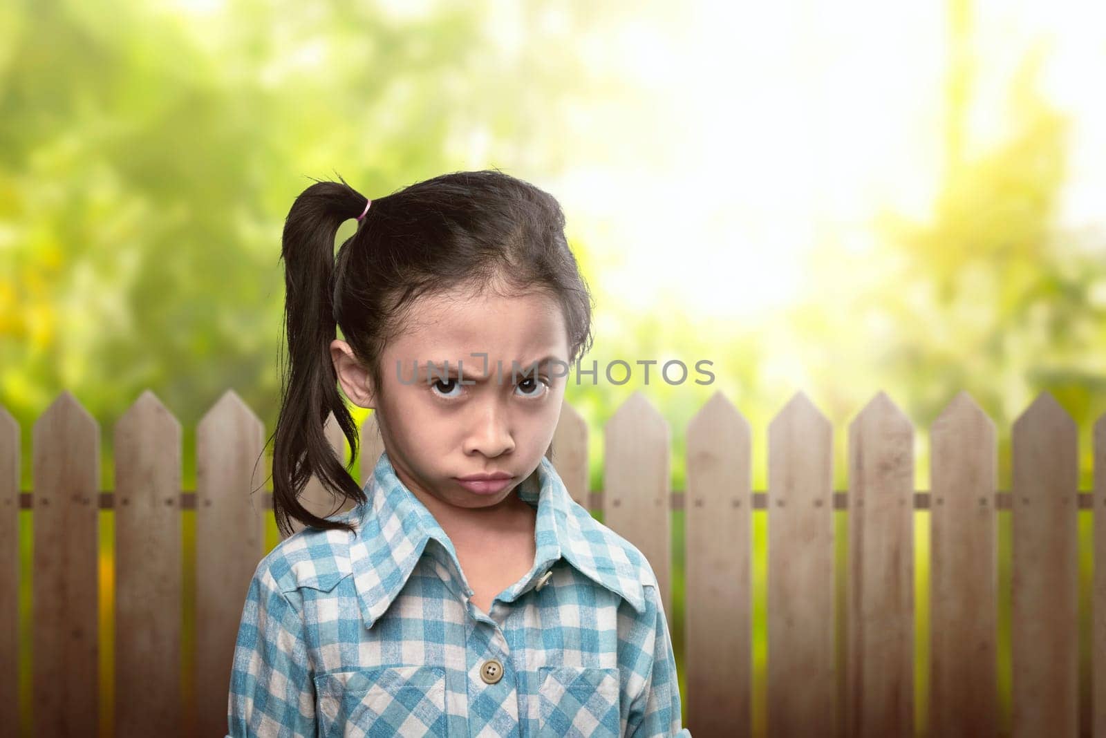 Sad asian kid in blue clothes with disbelief expression on the park