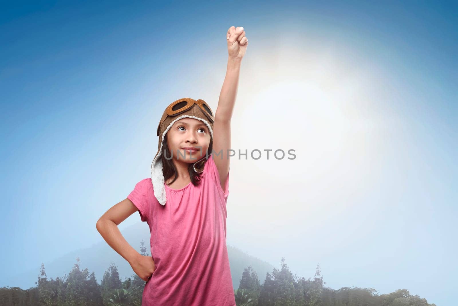 Smiling asian little girl in aviator helmet dreaming of becoming a pilot in the park