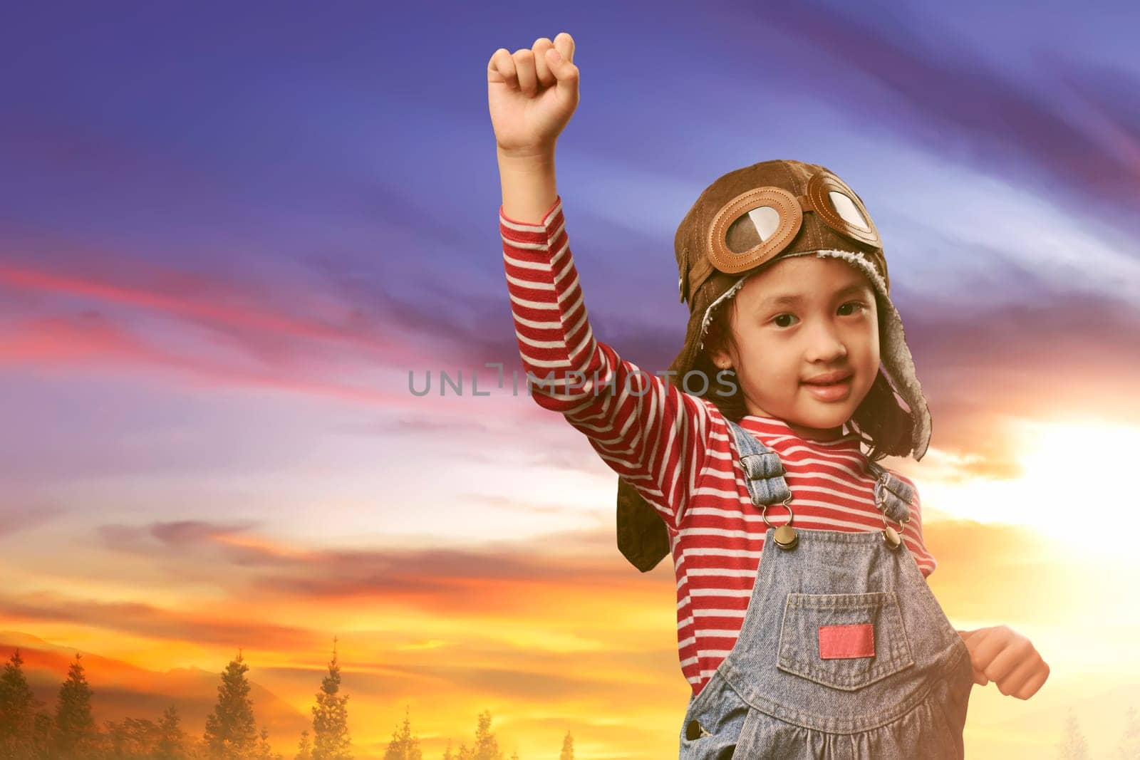 Beautiful asian child with pilot costume playing on the field at sunset