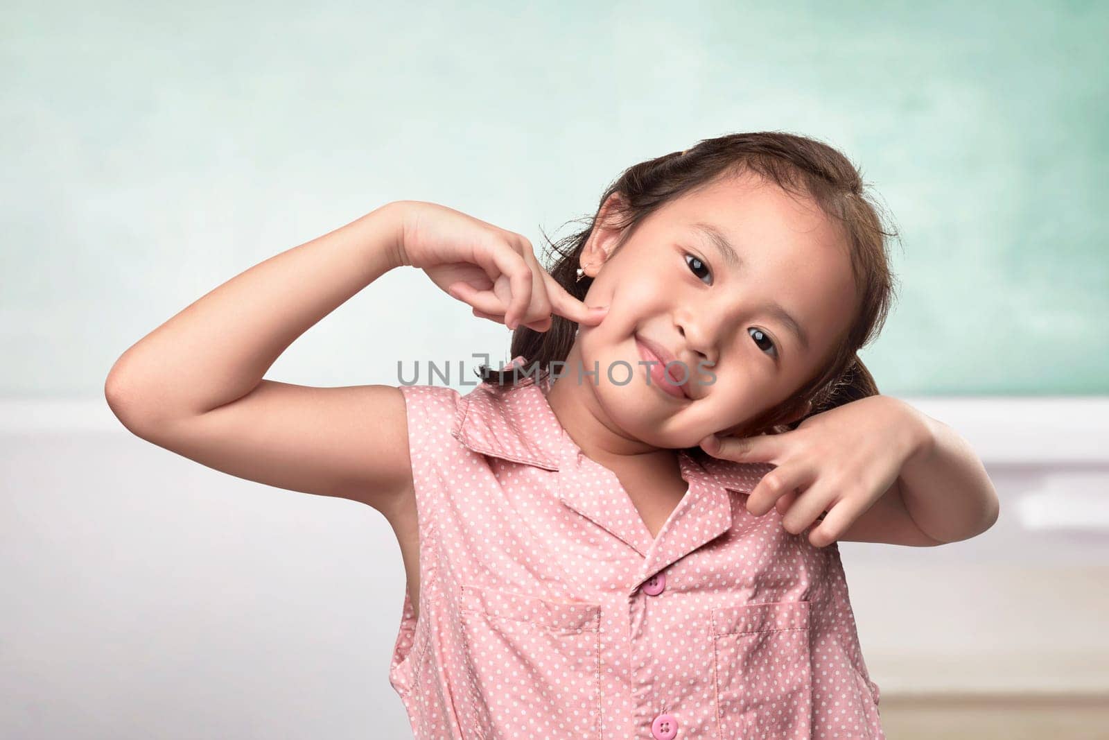 Cheerful asian little girl with funny face on the classroom