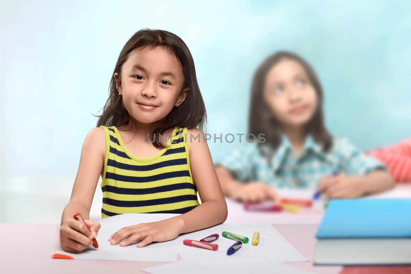 Group of asian little girl at the table and drawing with crayon in the classroom