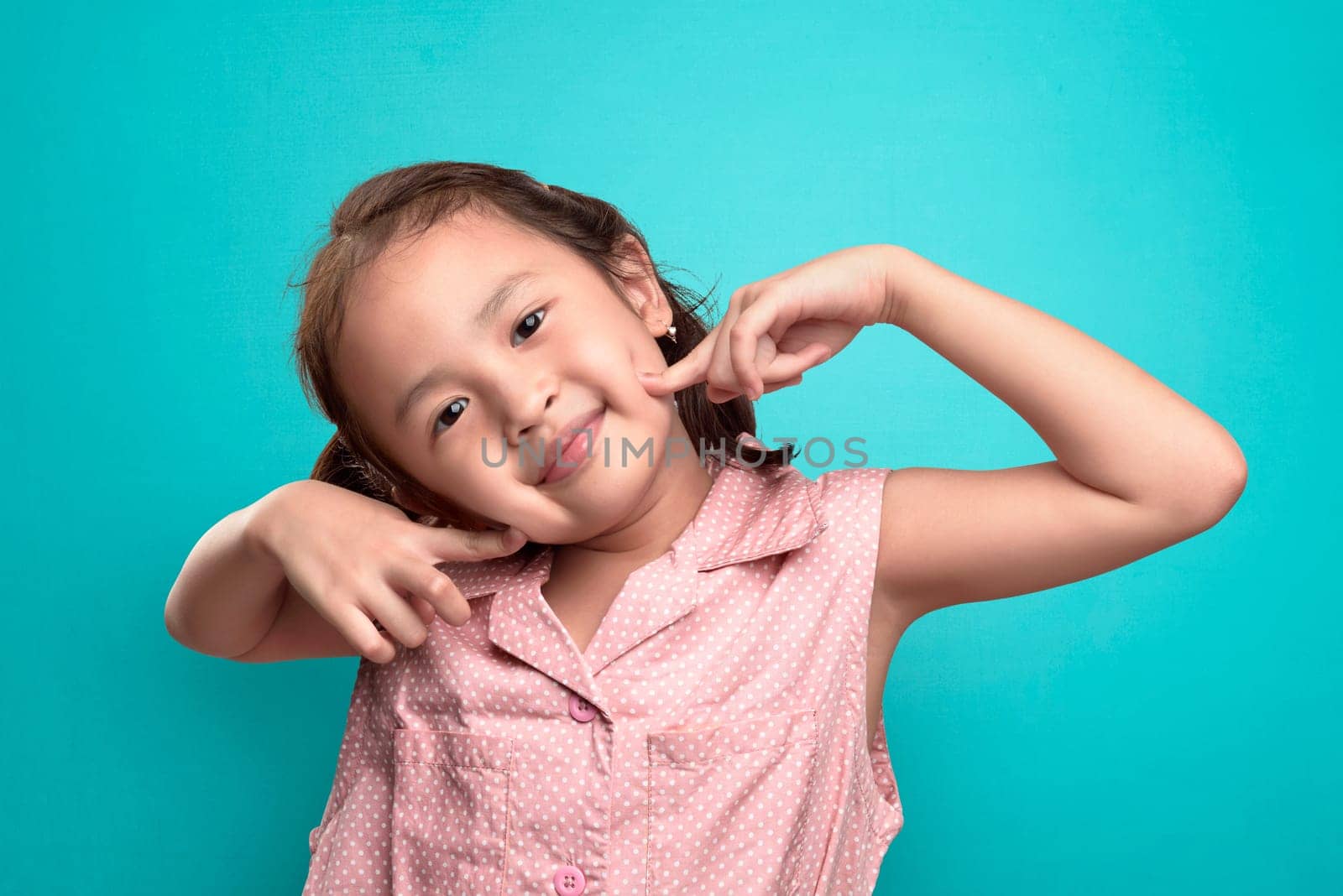 Happy asian little girl with funny expression against blue background