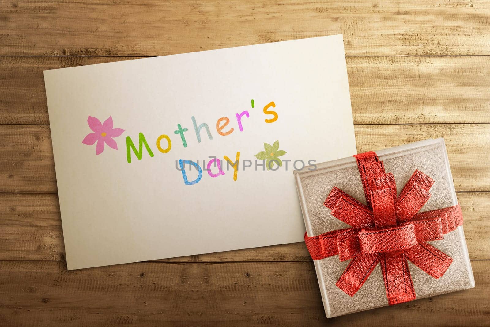 White gift box with Mother's day greeting on paper over wooden table