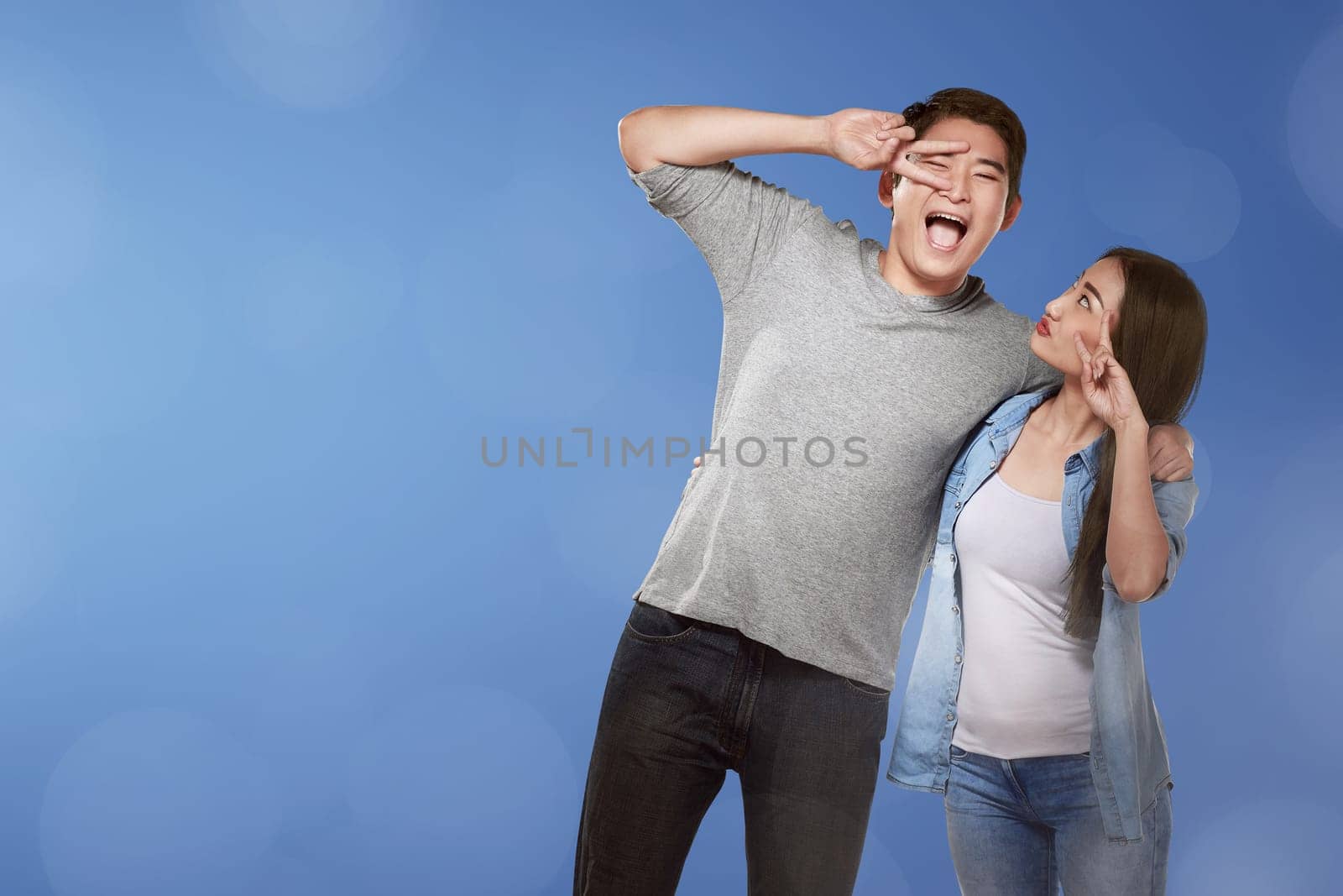 Romantic asian couple with funny expression against blue background