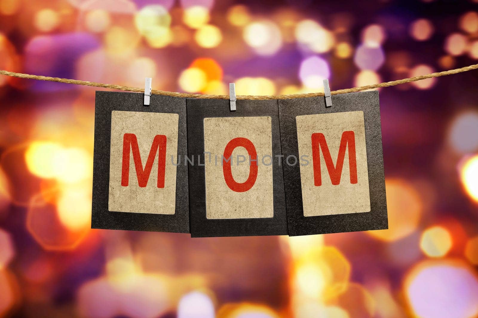 Mom word shape hanging with clothespin over blurred light background