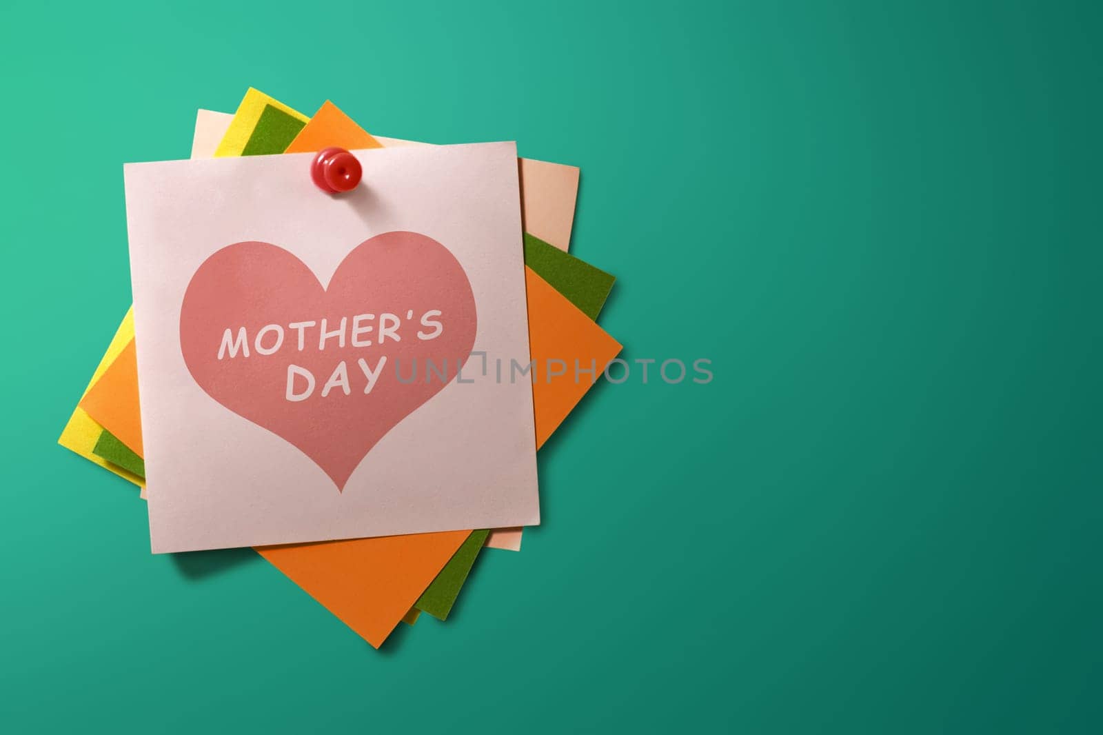 Mothers Day message written on stack of colorful paper note on green background