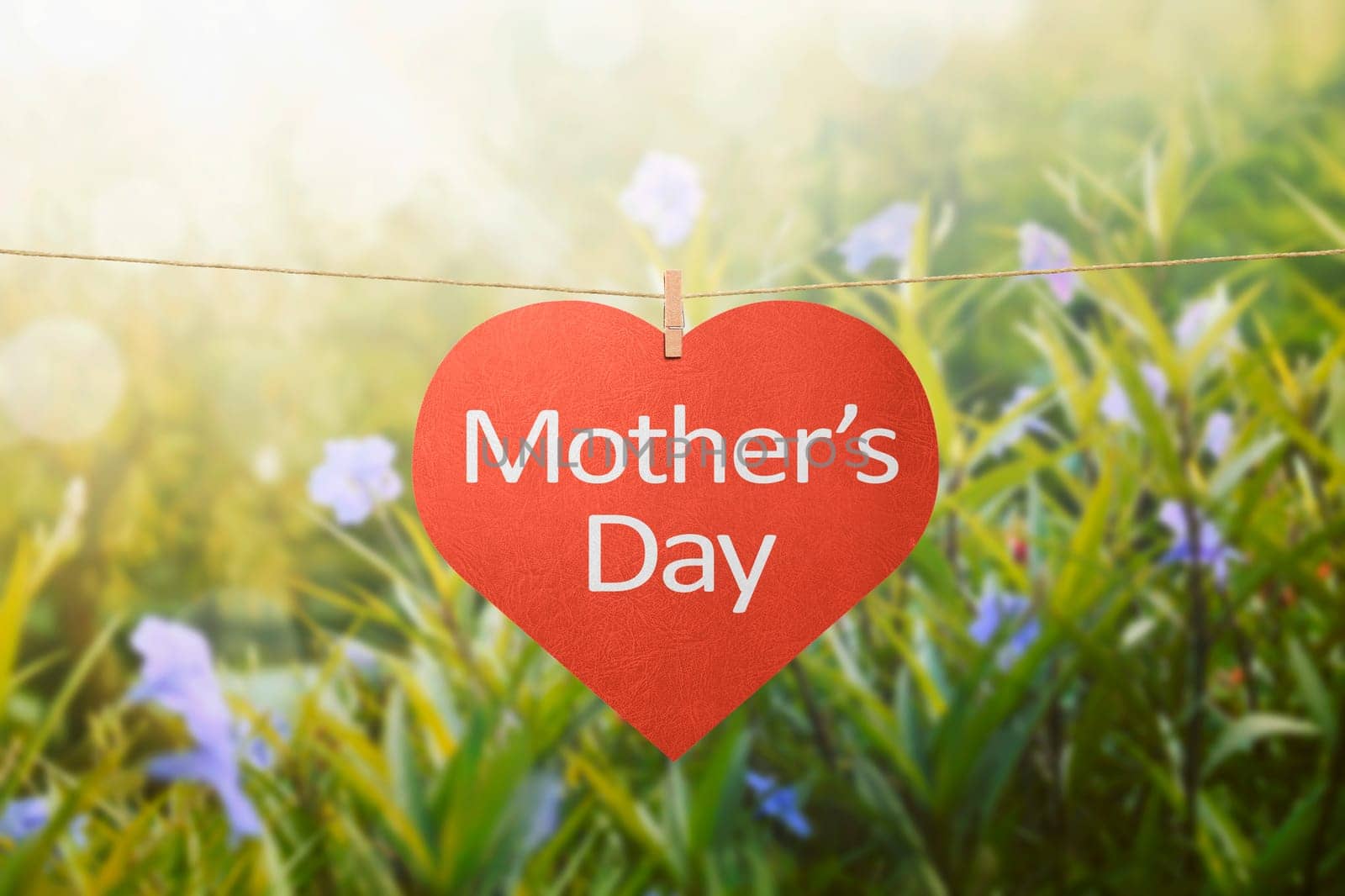 Mothers day message with felt hearts hanging with clothespins over green field background