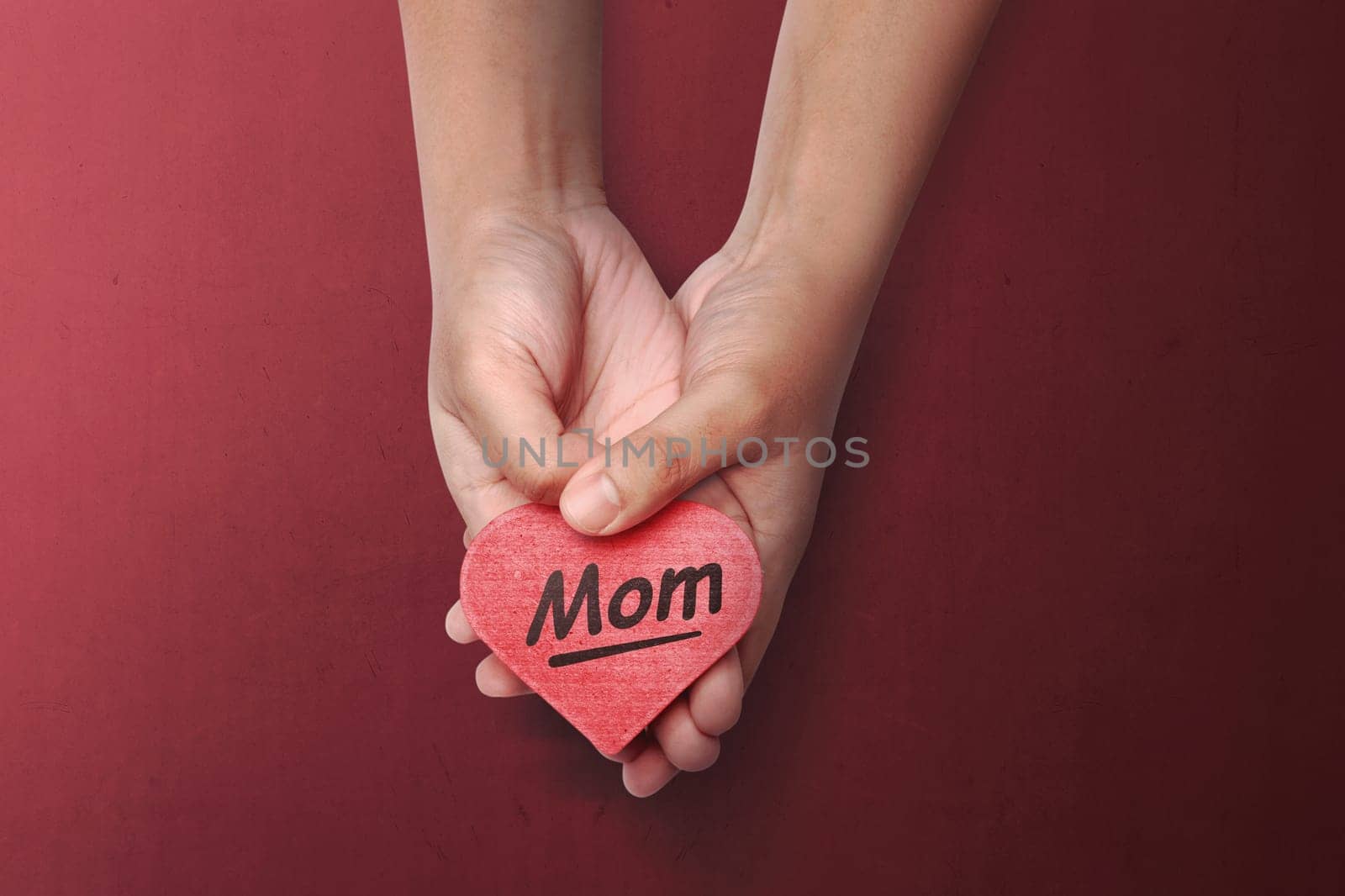 People hand holding red heart with Mother's Day message over red background