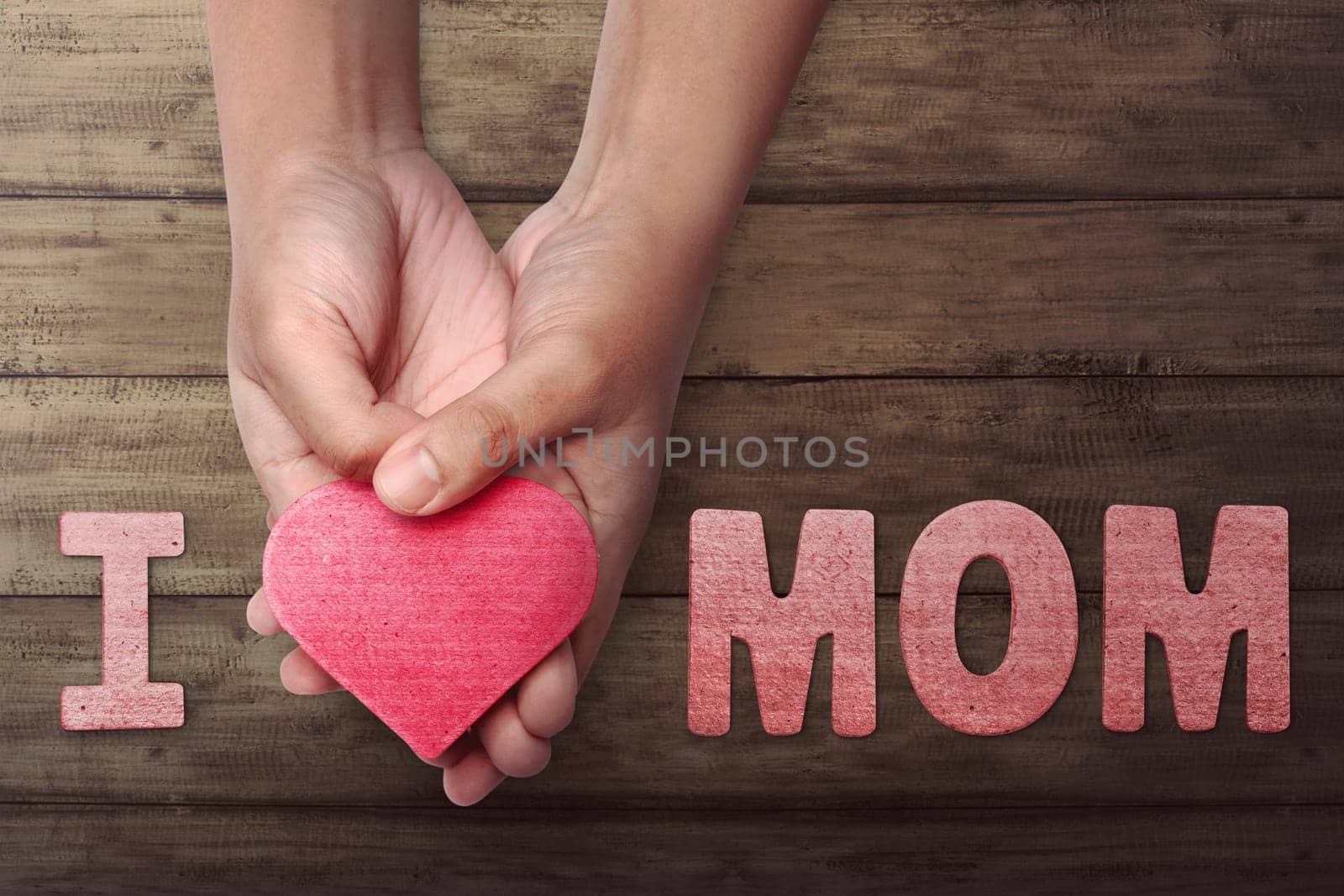 People hand holding red heart to make Mother's Day greeting in wooden table