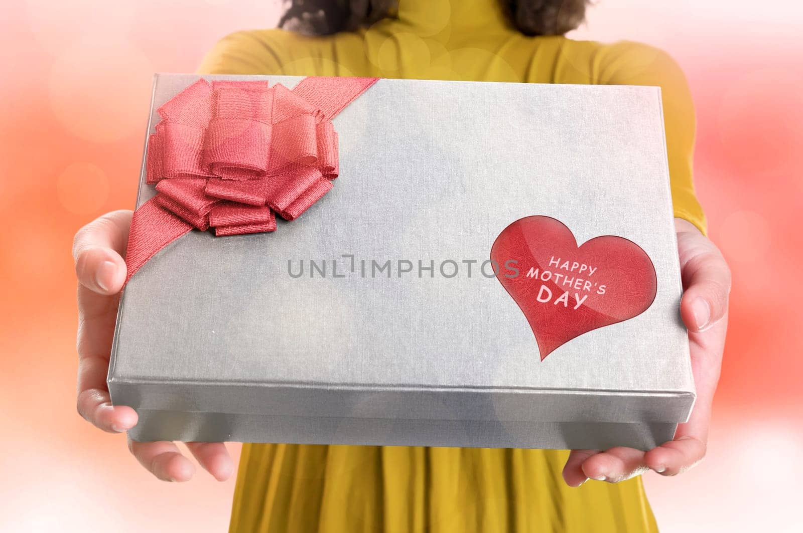 Girl holding a gift box with Happy mothers day message on heart shaped against blurred background