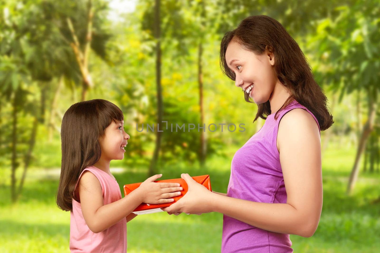 Portrait of happy mother with gift from her daughter in garden. Mothers day concept.