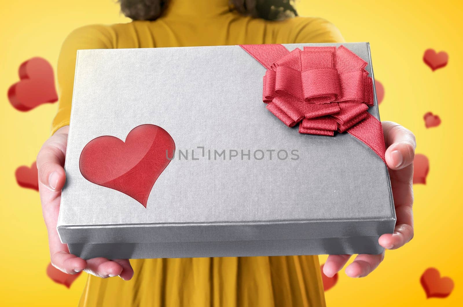 Hand holding a gift box with red ribbon and heart shape for mothers day over colorful background
