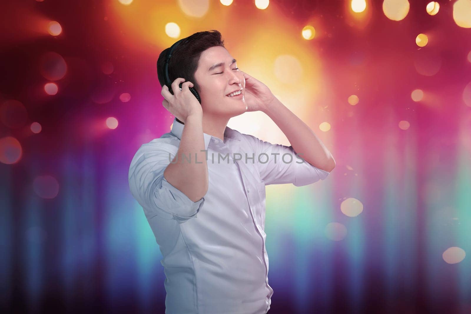 Cheerful asian man enjoying his favorite music in headphones with bokeh background