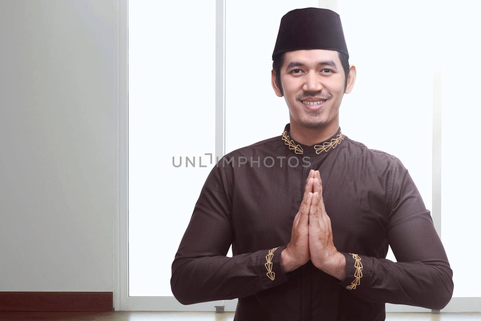 Young asian muslim man with black cap praying inside the room