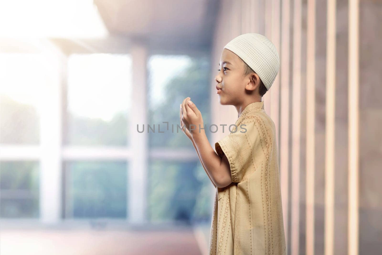 Portrait of asian muslim boy with white cap praying in the mosque