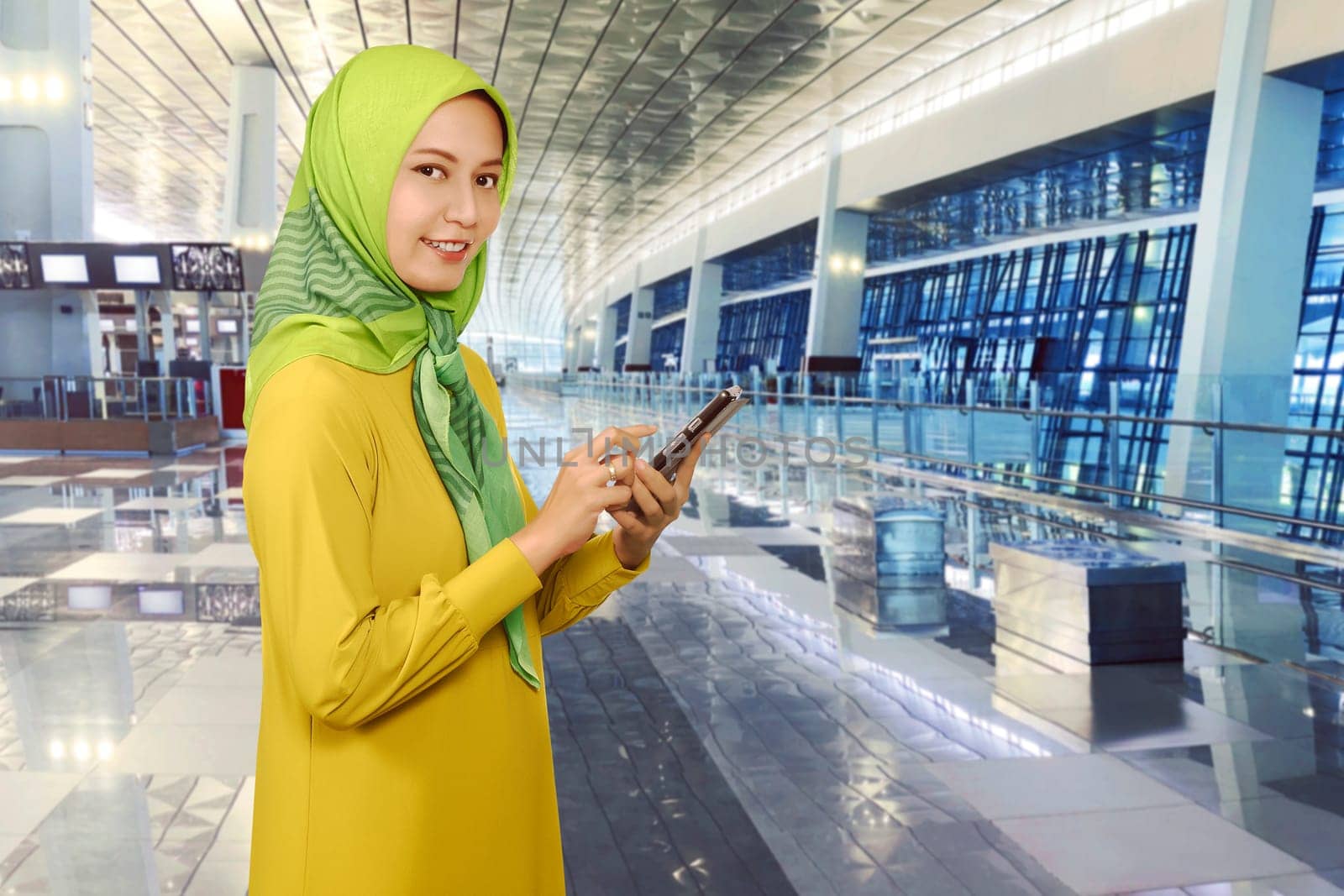 Young asian muslim woman messaging on a smartphone in the airport