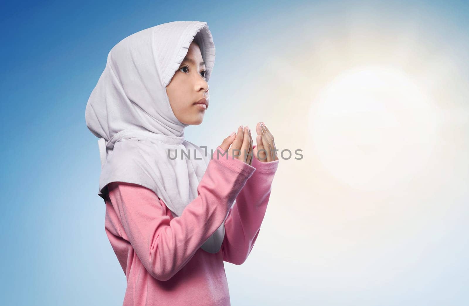 Little asian muslim girl praying to god over sunlight background