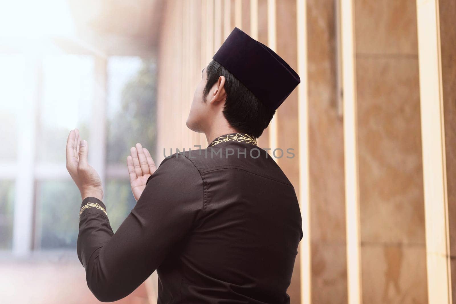 Rear view of asian muslim man with traditional dress praying in the mosque