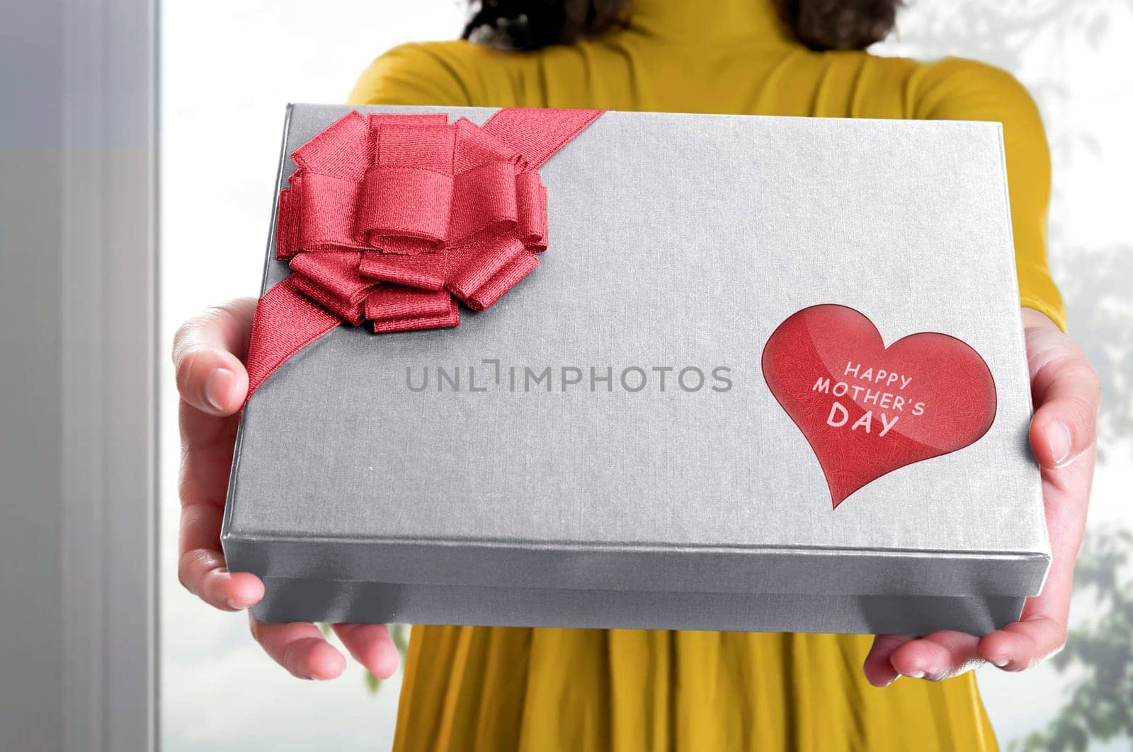 Girl holding a gift box with Happy mothers day greeting on red heart in the home