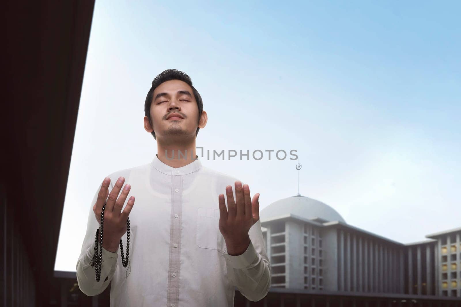Handsome asian muslim man praying with beads on the mosque