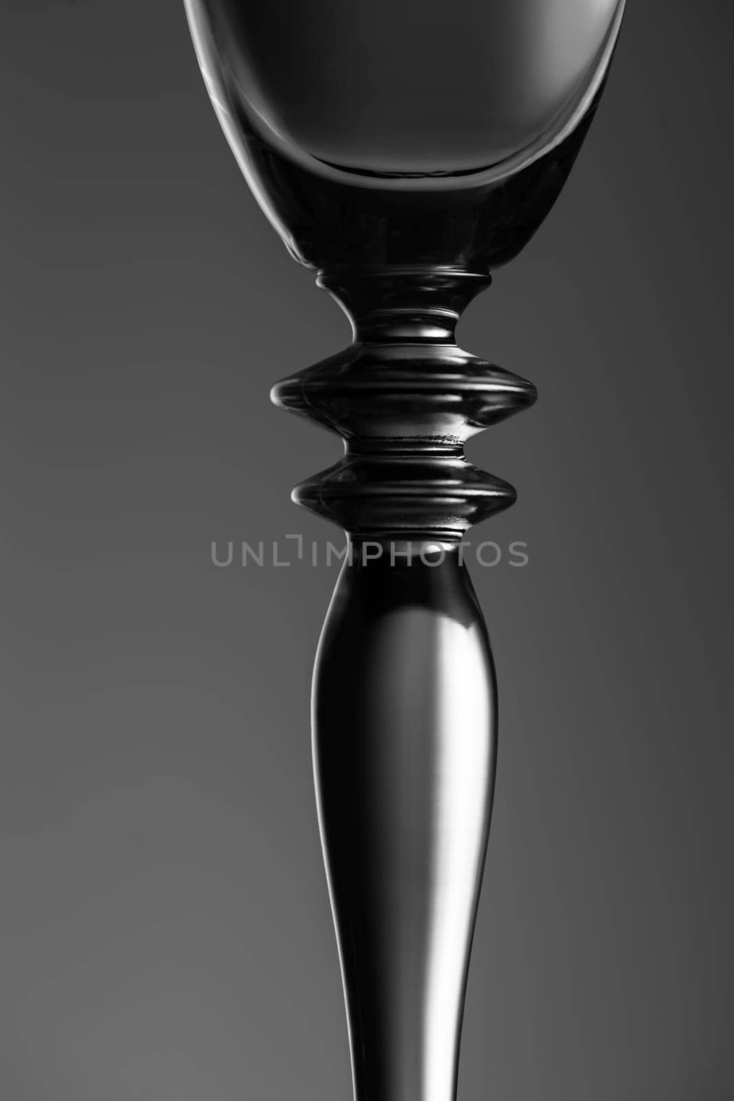 Detailed view of the middle part of a champagne glass with brightness gradient in the background  monochrome.