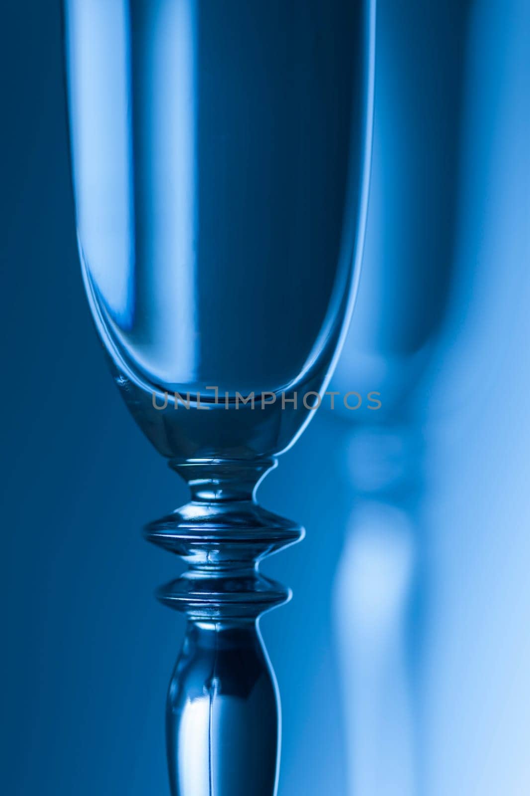 Upper part of a champagne glass in front of a brightness background toneed blue.