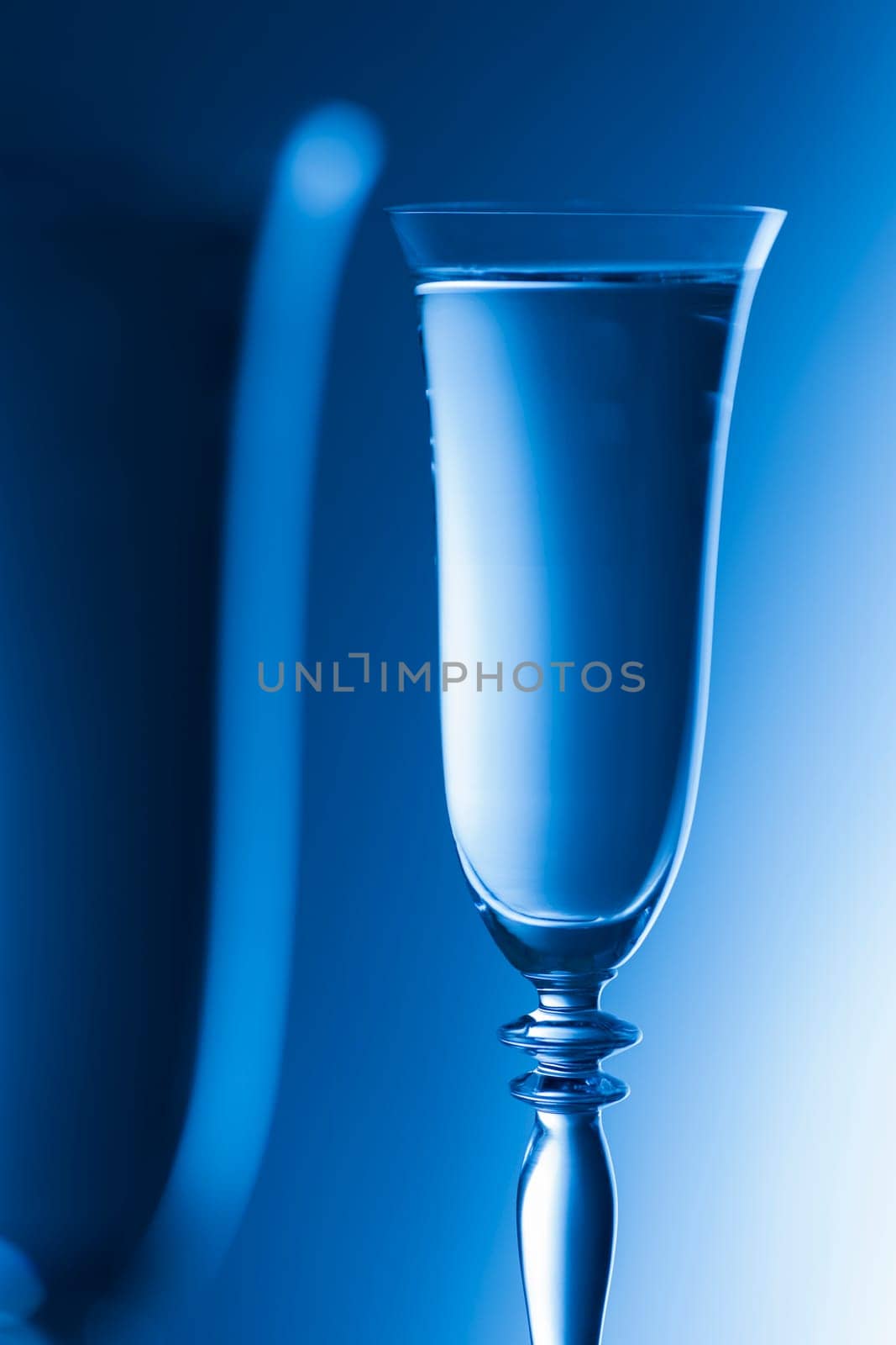 Detailed view of the tops of two champagne glasses against a background with brightness gradient. The focus is on the rear glass.