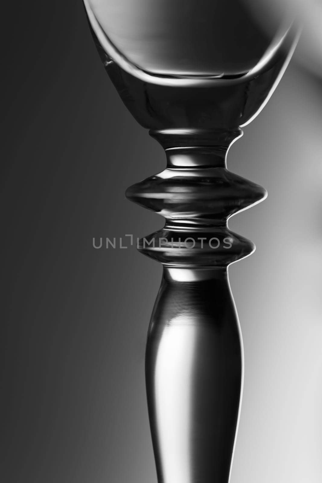 Detailed view of the middle part of a champagne glass with brightness gradient in the background  monochrome.
