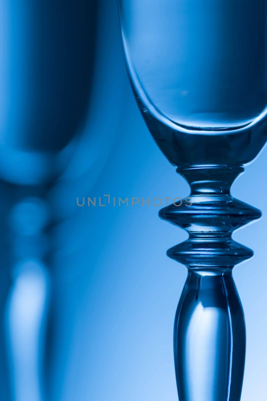 Detailed view of the middle parts of two champagne glasses Brightness running background shaded blue. The focus is on the front glass.