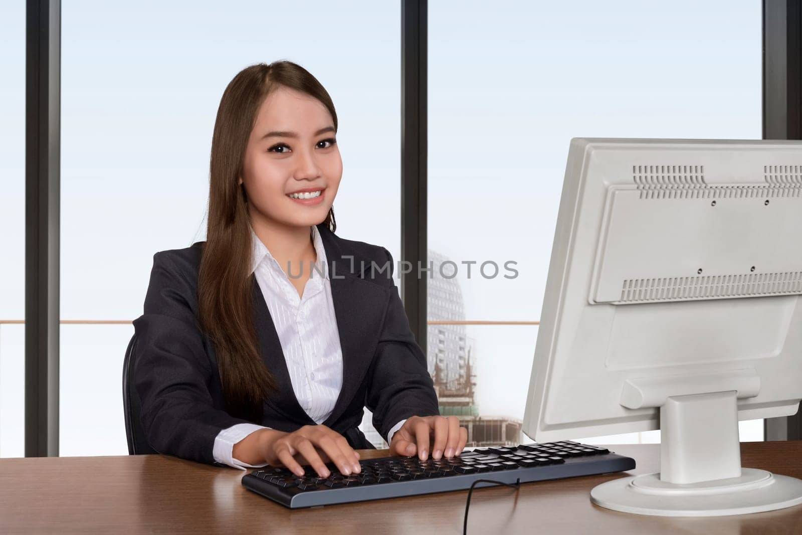 Young asian business woman working with computer against window glasses background