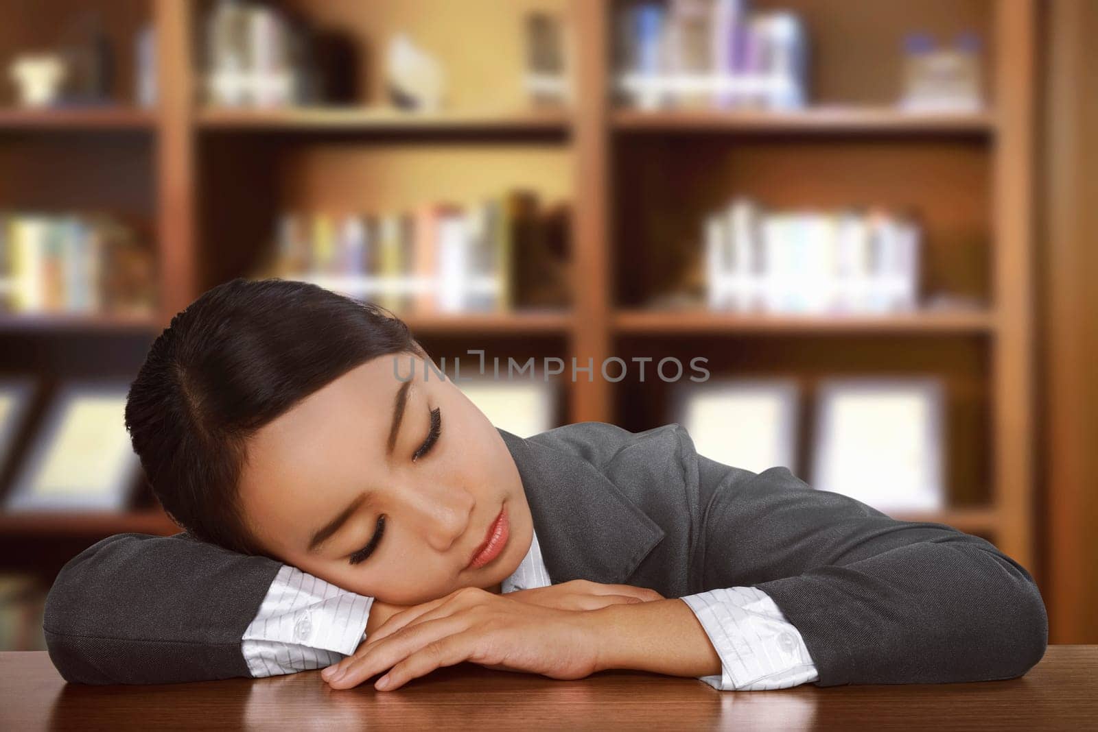 Young tired asian woman sleeping on desk at office
