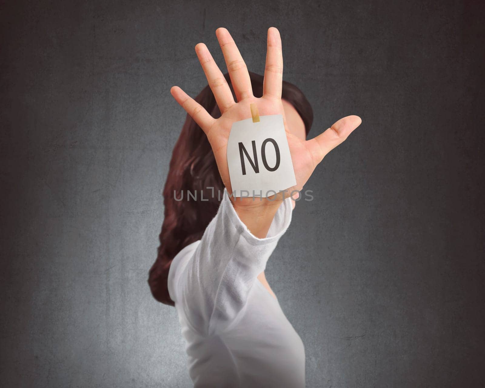 Side view of asian woman showing NO note on her hand against black wall background