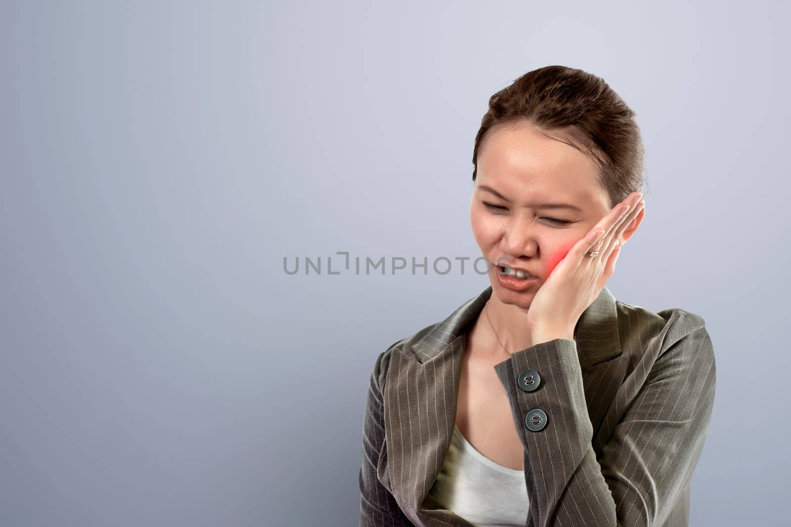 Young asian business woman sensed toothache against gray background