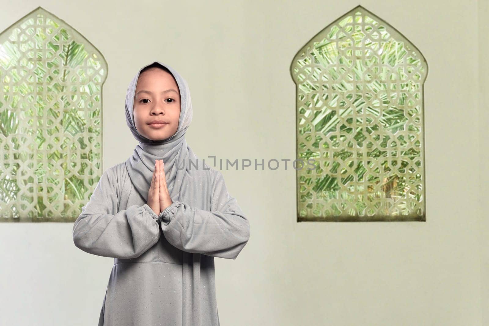 Little asian muslim kid with veil praying to god on the mosque