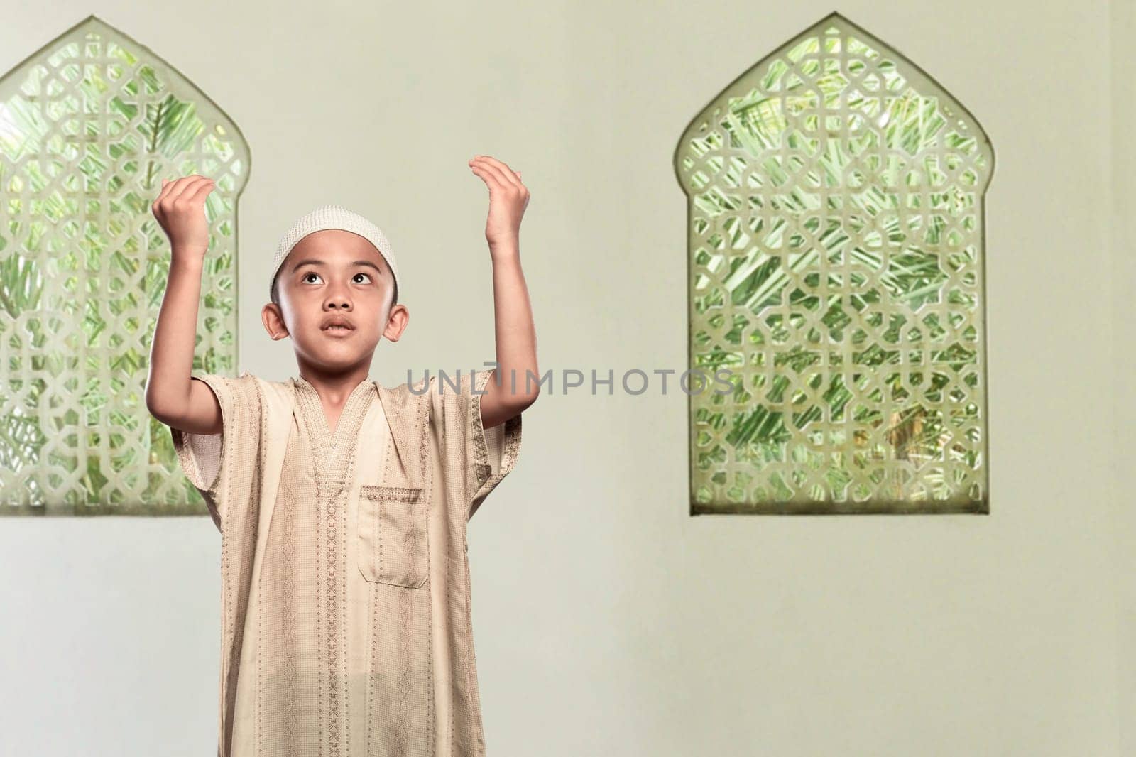 Religious asian muslim child standing praying to god in the mosque