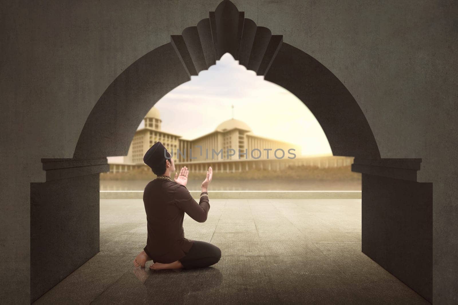 Rear view of asian muslim man praying to god with mosque view background