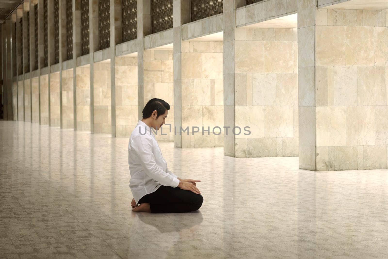 Handsome asian muslim man kneeling and praying to god in the mosque