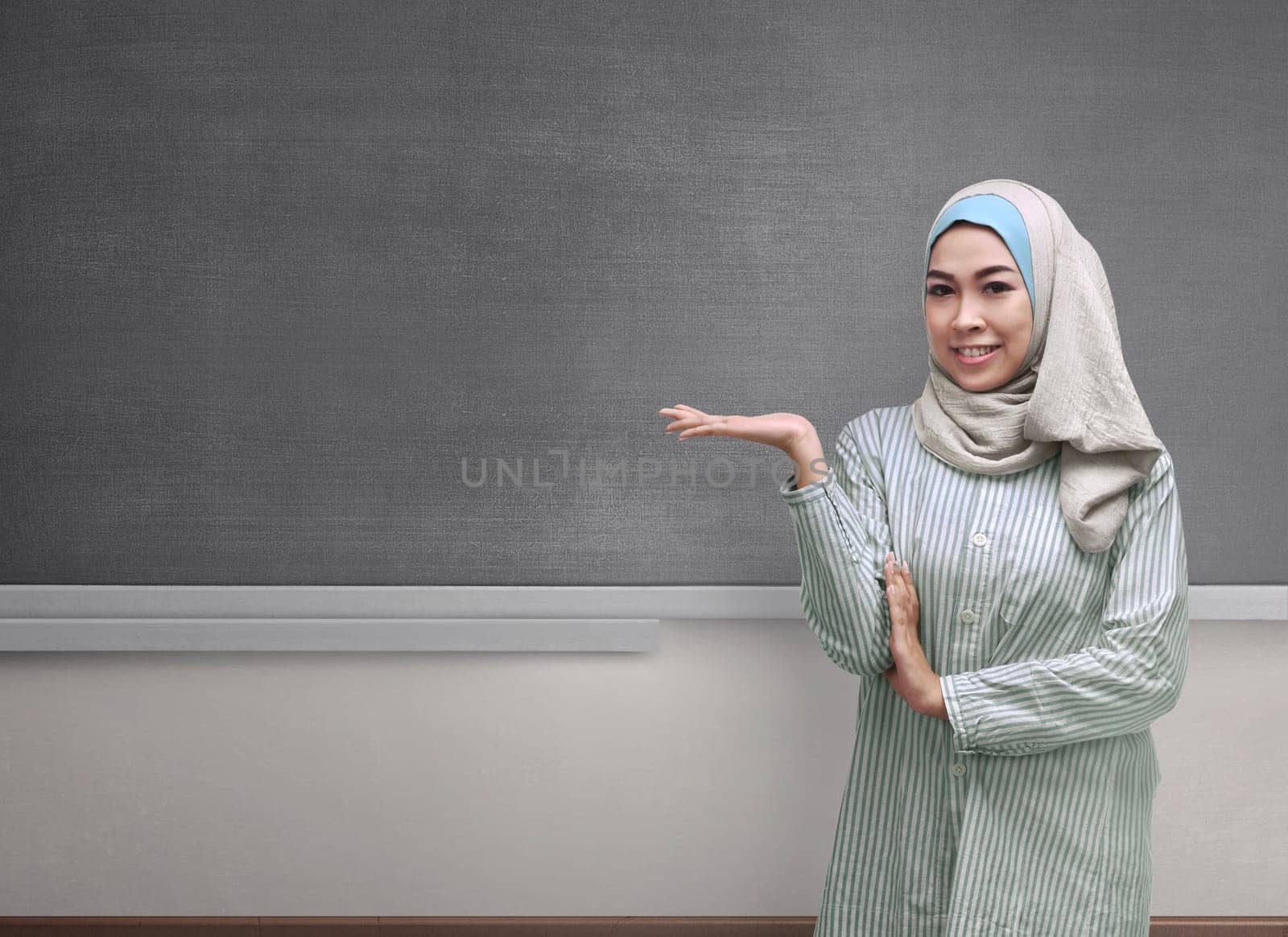 Beautiful asian muslim woman wearing hijab showing copyspace area on the blackboard