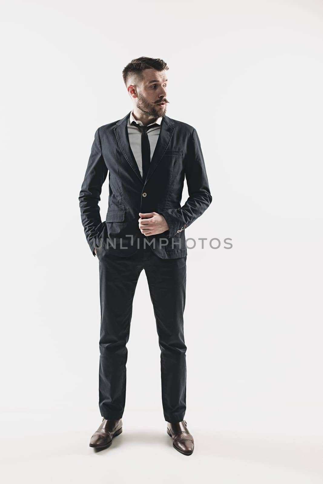 Portrait of stylish handsome young man standing at studio against white. Man wearing jacket