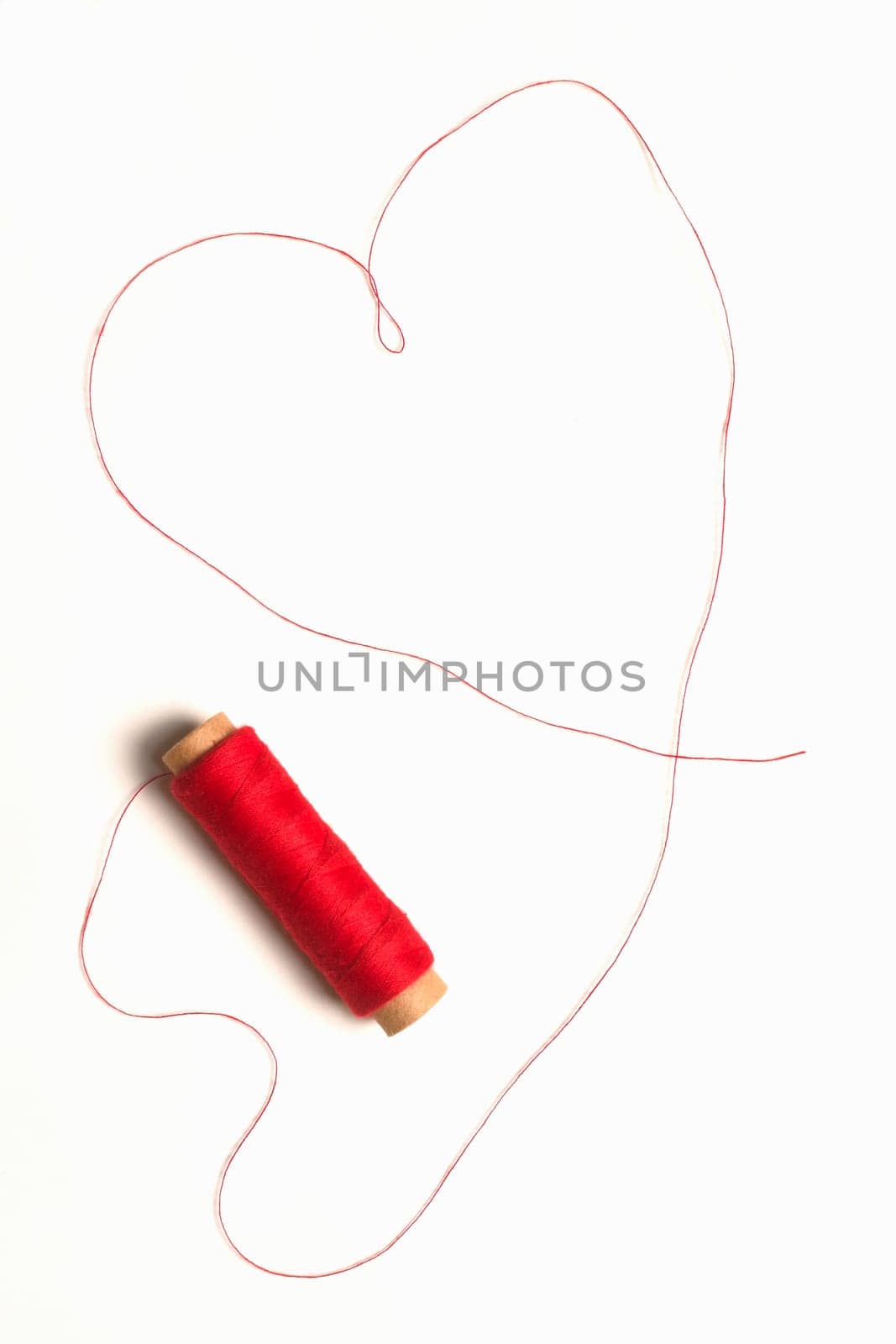 Heart shape from red thread on white background.