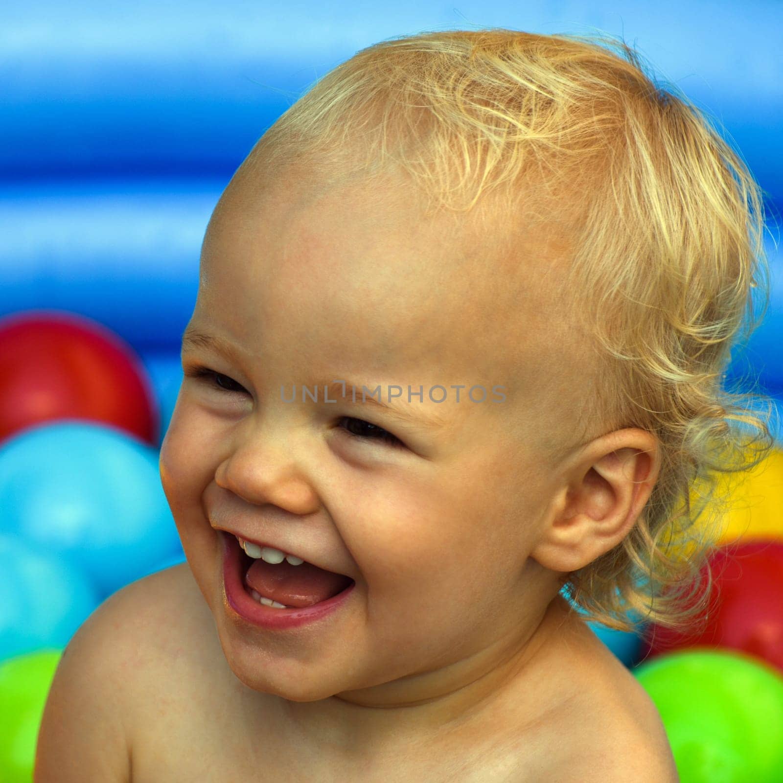 Portrait about a laughing child on colorful background.