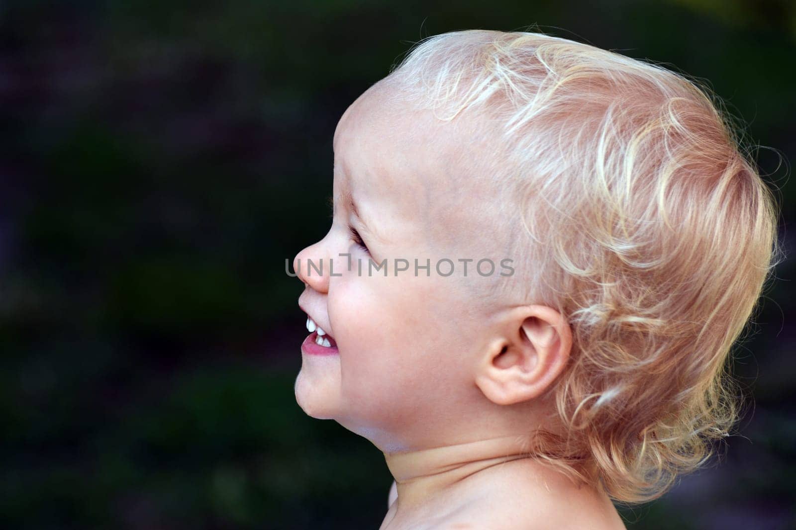 Portrait about a happy little child on green background, profile view.