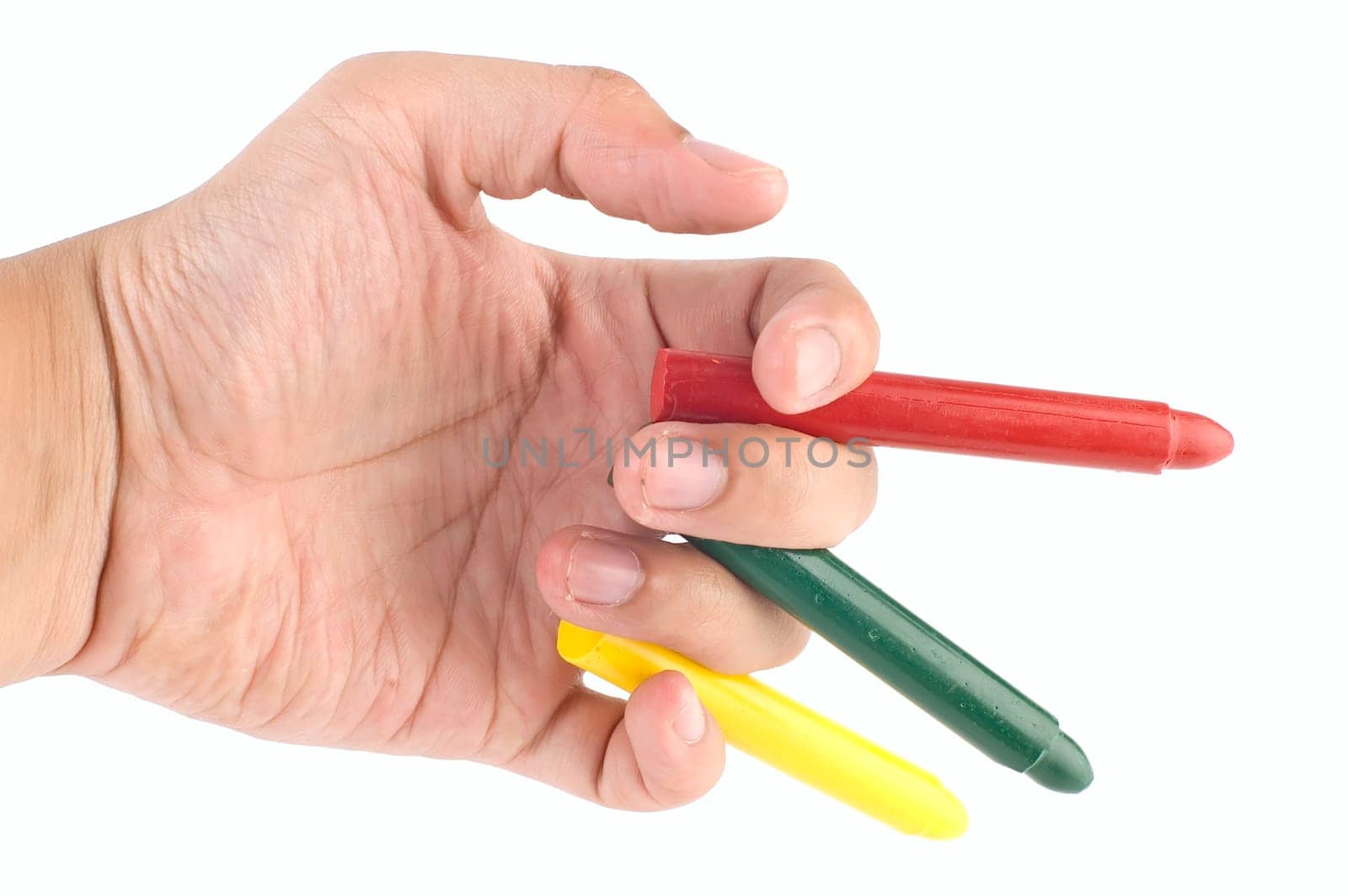 Hand holds orange, green, and yellow crayon on white background