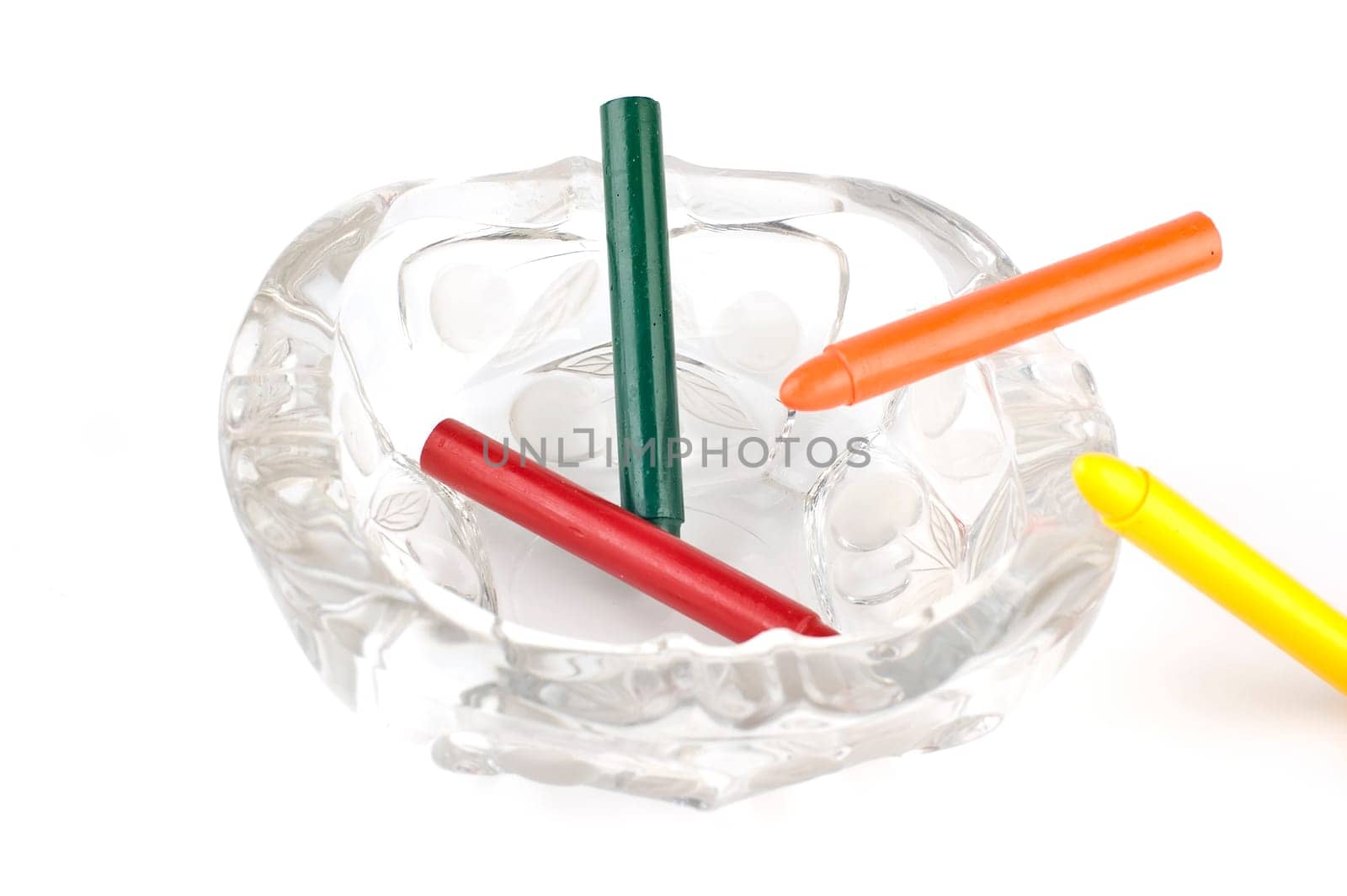 Four wax crayons on the ashtray. The colors are red, green, orange, yellow