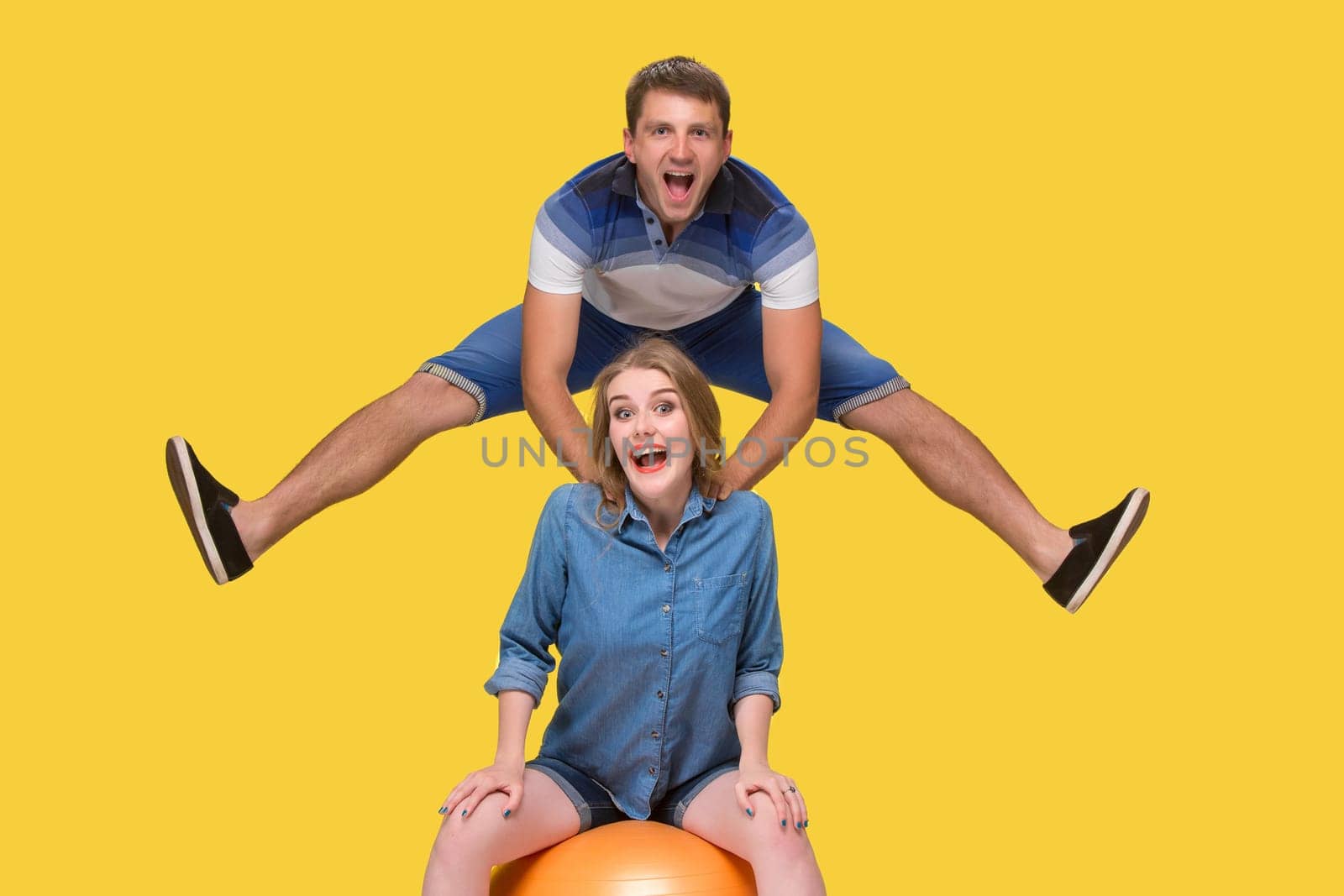 Portrait of a young couple jumping against yellow studio background