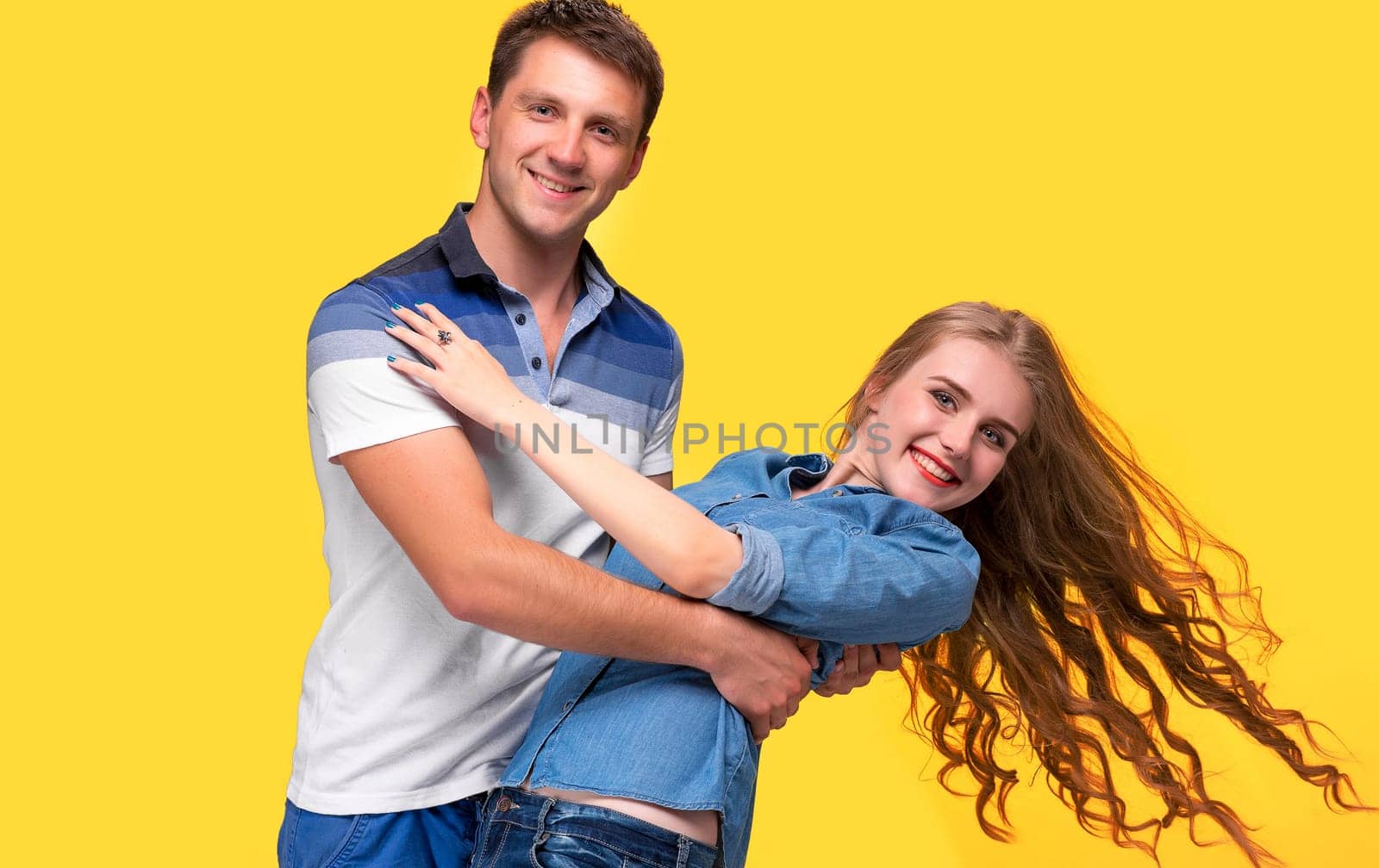 Portrait of a young couple standing against yellow studio background